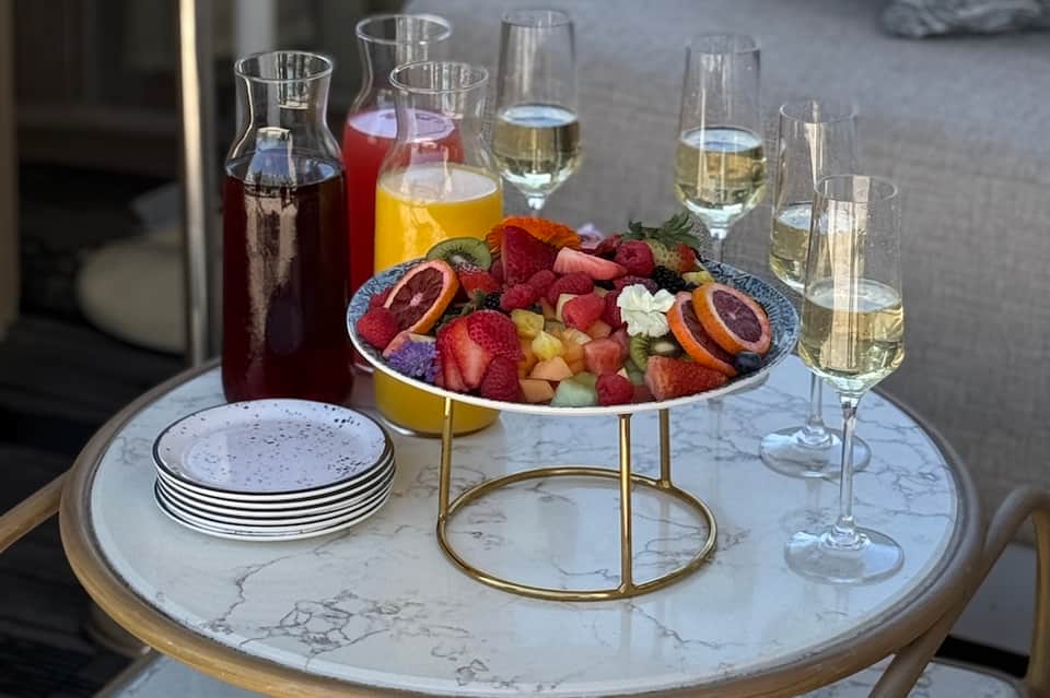 Marble table with appetizer platter, wine glasses, and cocktail pitchers for entertaining