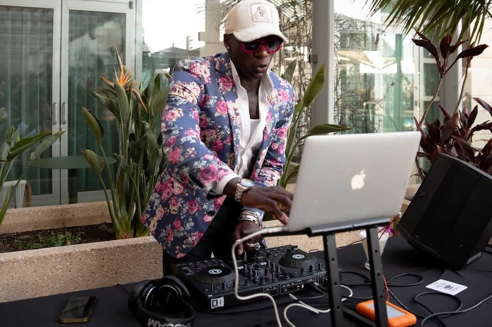 Man in floral blazer working on laptop outdoors surrounded by tropical plants