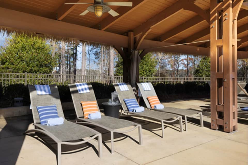 Covered patio with striped lounge chairs and ocean view overlooking trees and water