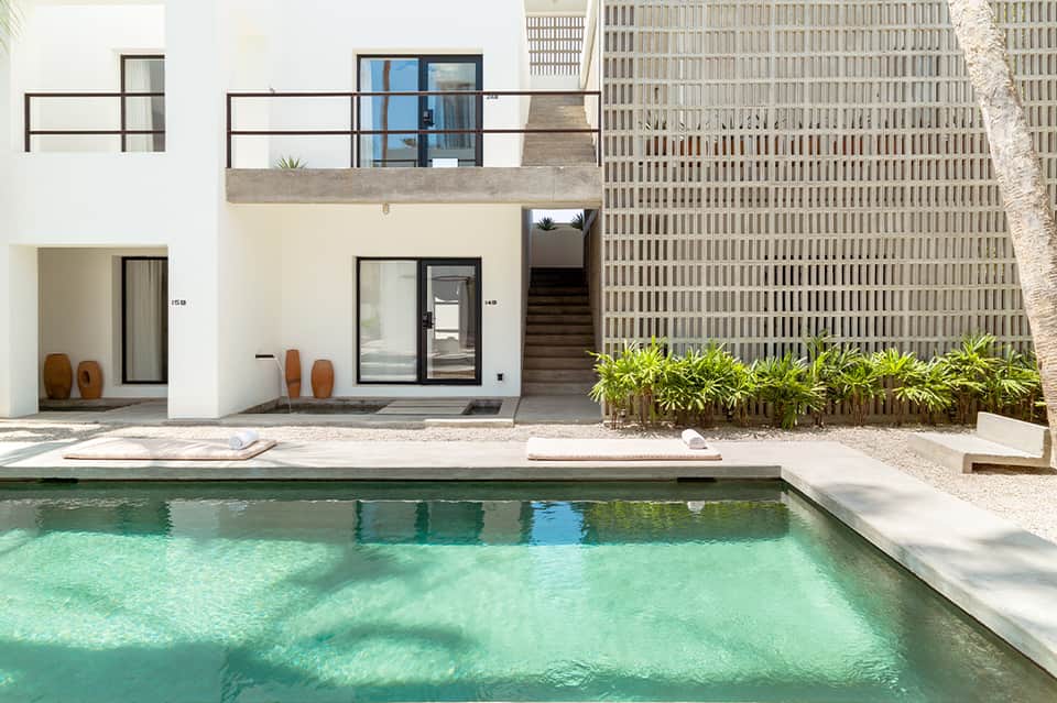 Modern poolside villa with white exterior, turquoise water, and minimalist architectural design