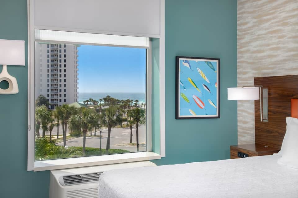 Beachfront hotel room with turquoise walls, ocean view, and palm trees