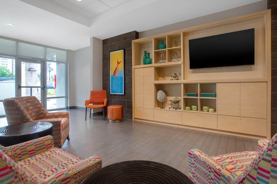 Modern hotel lobby with colorful patterned seating and wood shelving unit