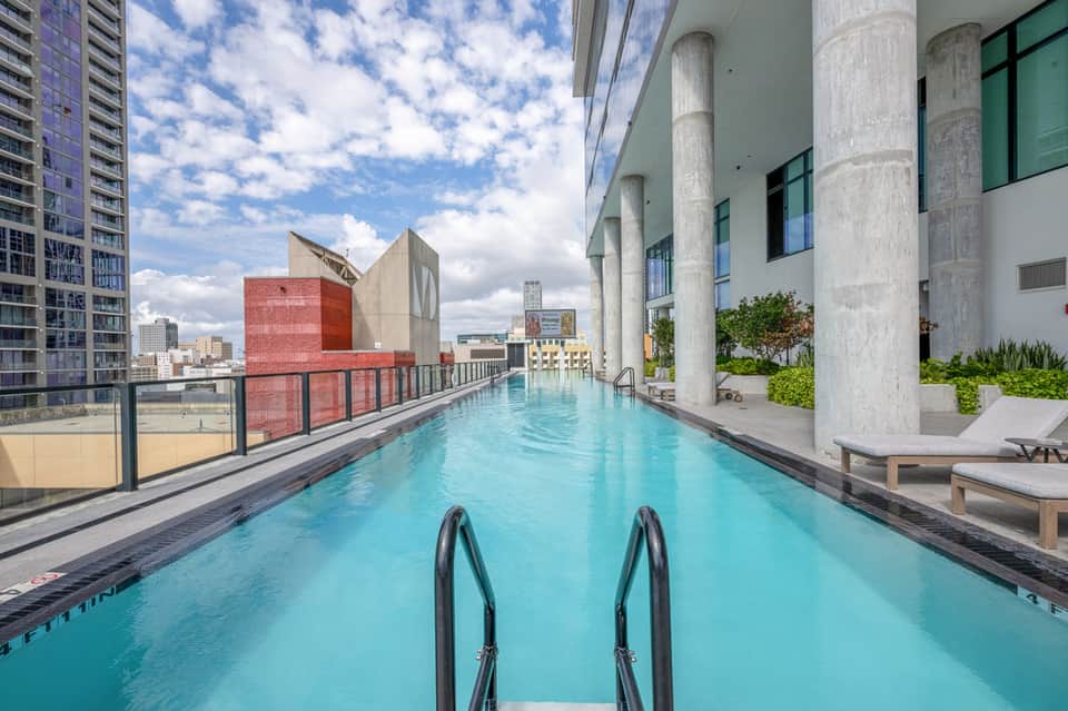 Rooftop lap pool at urban hotel with city skyline and mountain views