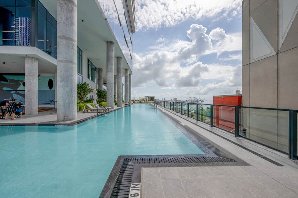 Rooftop infinity pool overlooking urban skyline with concrete columns and metal railings