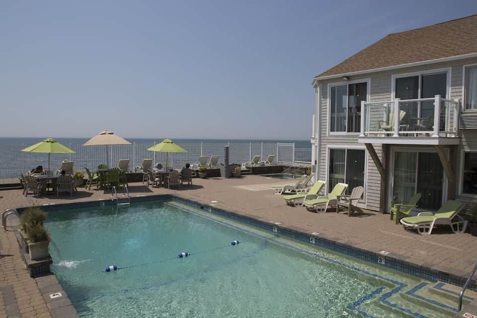 Oceanfront deck with swimming pool, lime-green umbrellas, Adirondack chairs, and ocean view