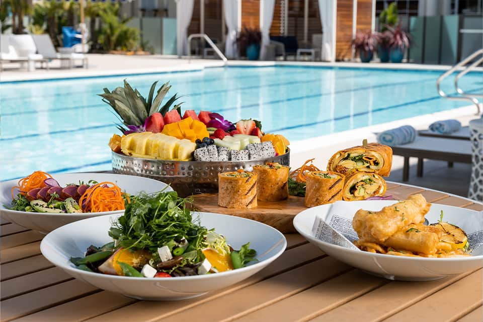 Poolside dining display with fresh fruit platter and appetizers by the water