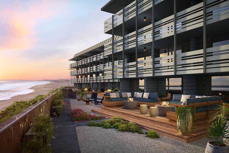 Modern beachfront resort at dusk with slatted railings, firepit seating, and ocean views