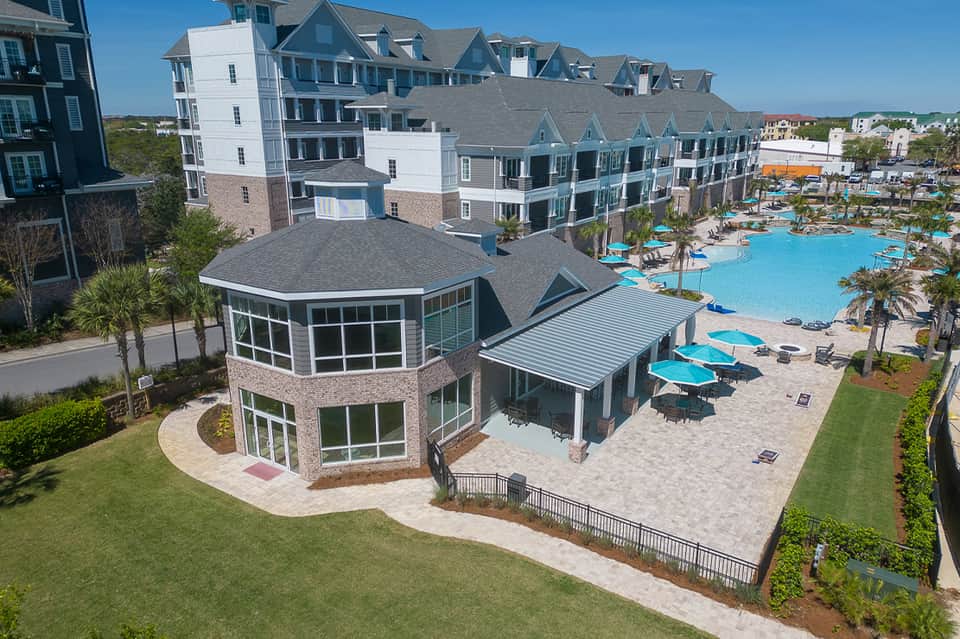 Coastal resort complex with pool, beach umbrellas, and residential-style buildings