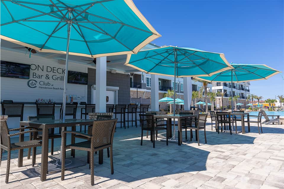 Outdoor poolside dining area with turquoise umbrellas and coastal resort atmosphere