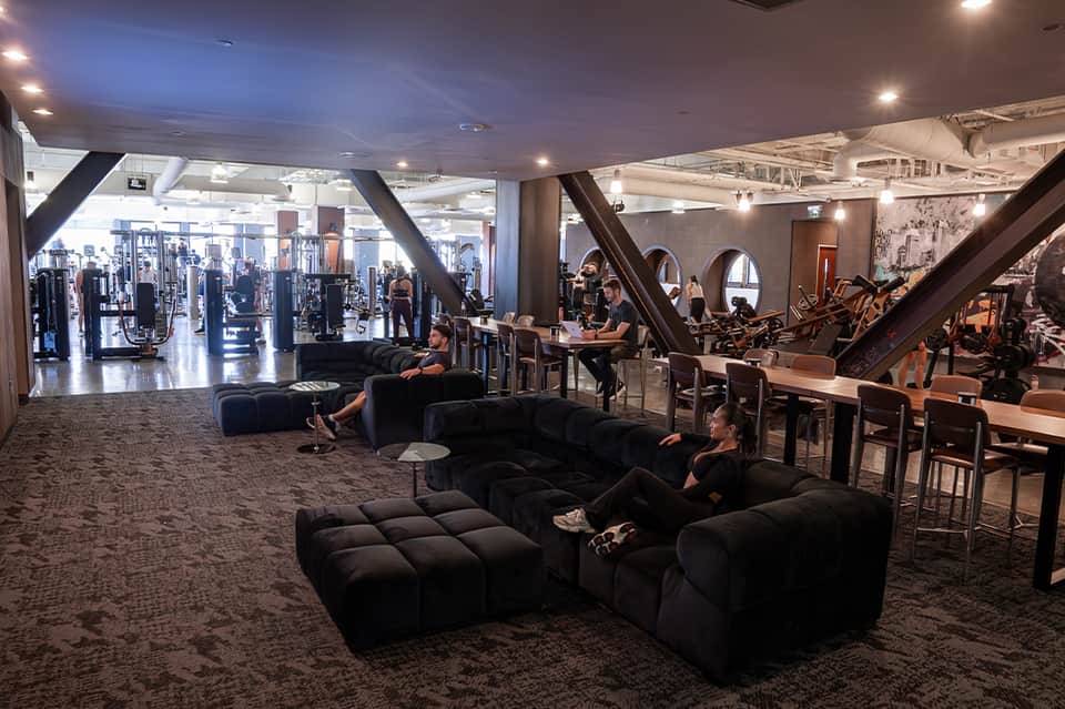 Modern hotel fitness center with gym equipment and seating area with large windows
