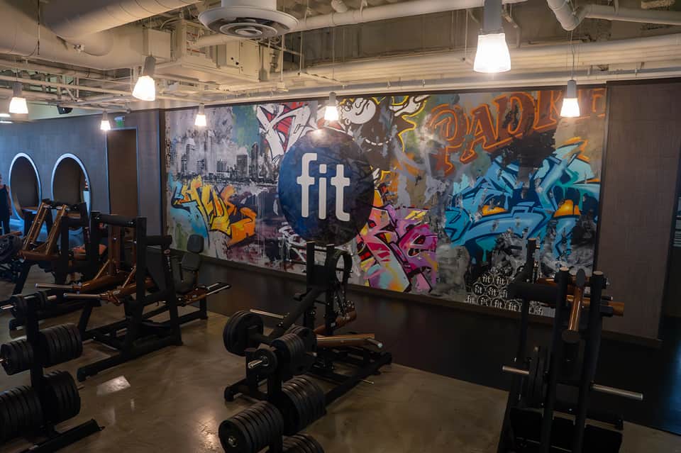 Modern gym with colorful graffiti wall art, dumbbells, and fitness equipment with FIT logo