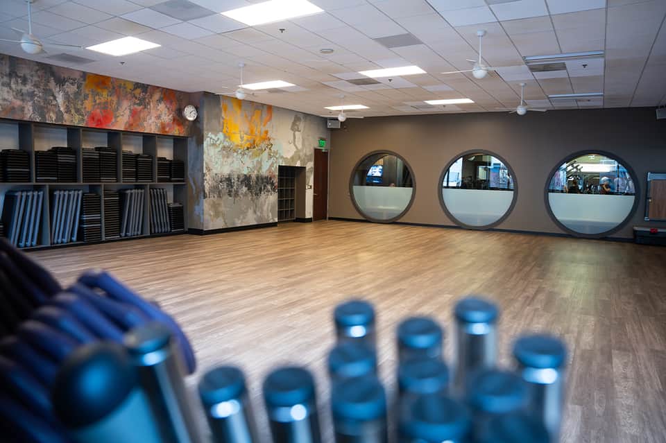Fitness studio with wooden flooring, circular mirrors, and colorful wall art