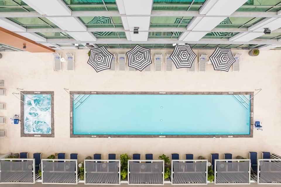 Overhead view of rectangular pool with striped umbrellas, loungers, and glass ceiling