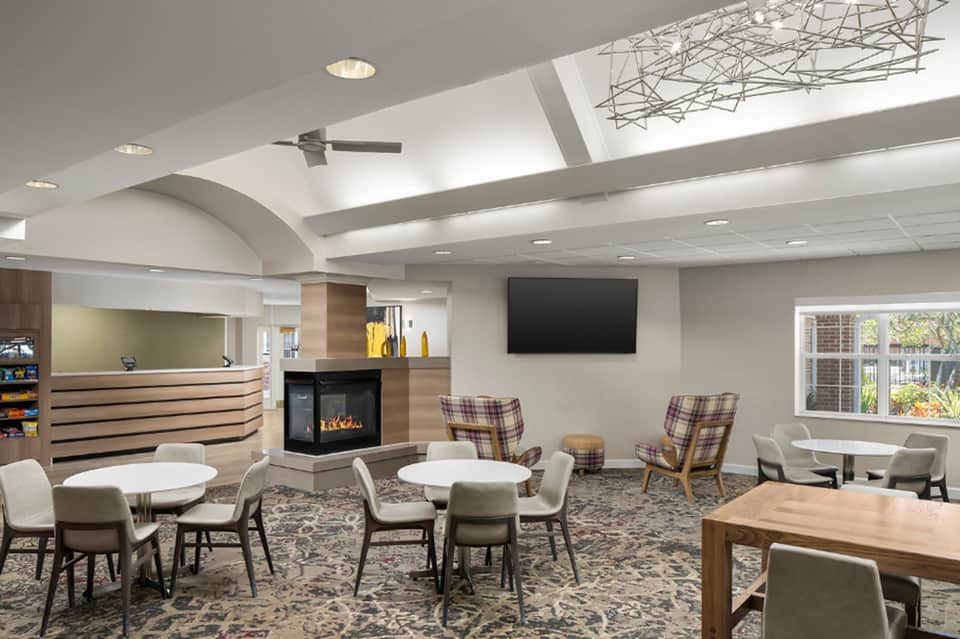 Modern hotel lobby lounge with fireplace, skylight, seating areas, reception desk, and contemporary decor