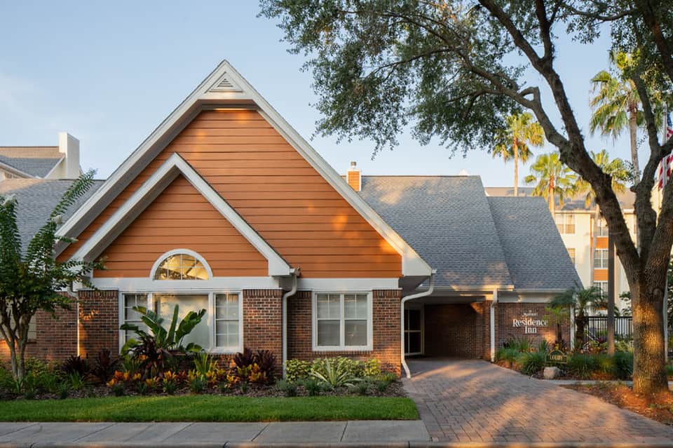 Brick residential inn entrance with manicured landscaping and covered entryway