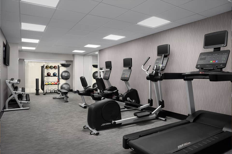 Modern fitness center with cardio equipment, exercise bikes, weight rack, and mirrors