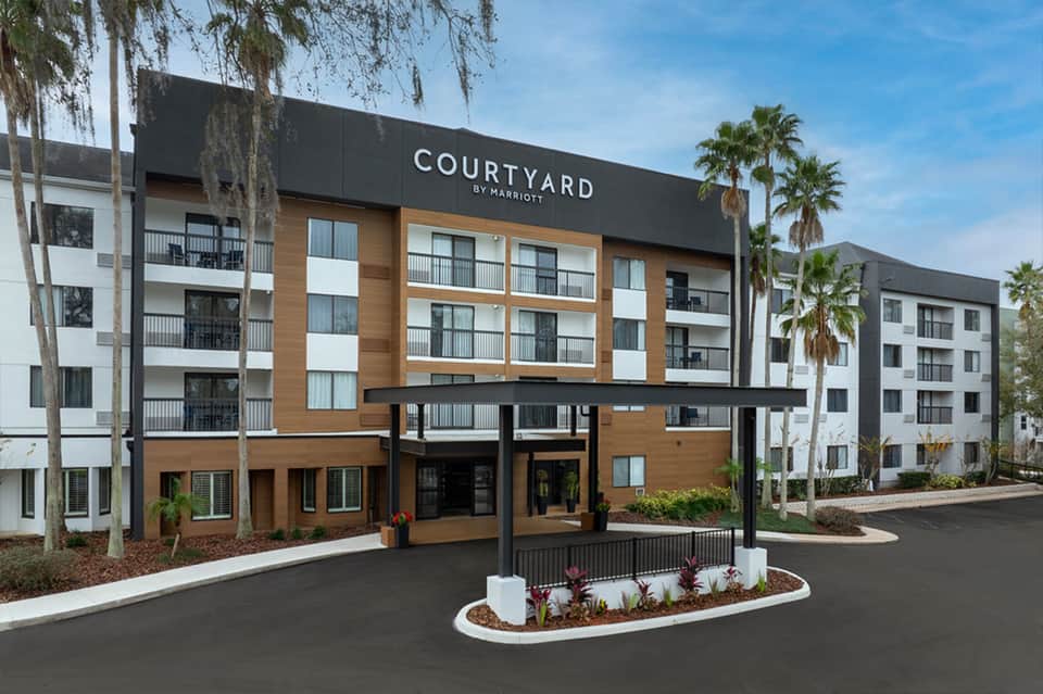 Courtyard by Marriott exterior featuring wood and metal facade, palm trees, and modern architecture