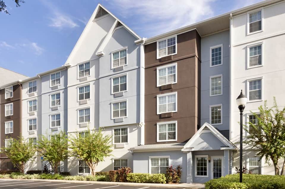 Contemporary hotel exterior with white and brown facade, gabled roofline, and landscaping