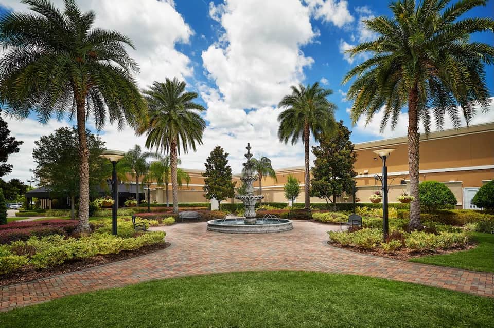 Landscaped courtyard with central fountain, palm trees, and manicured gardens