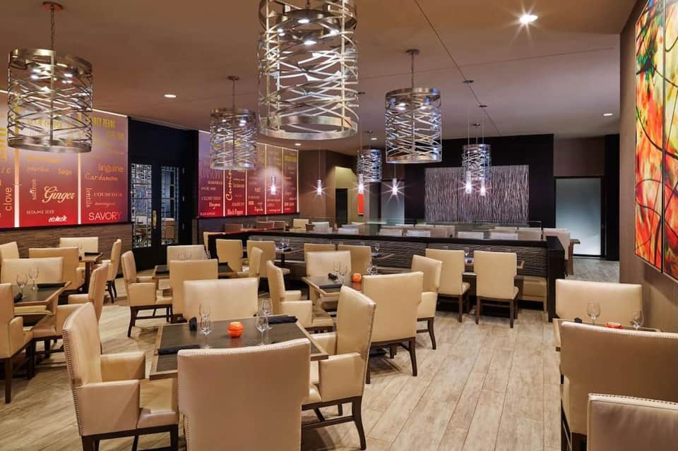 Contemporary hotel lounge with cream upholstered chairs, decorative pendant lights, and modern interior design elements