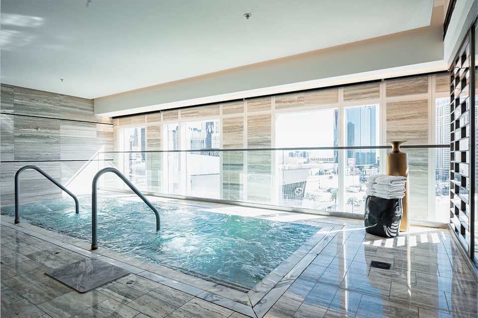 Indoor swimming pool with floor-to-ceiling windows overlooking city skyline