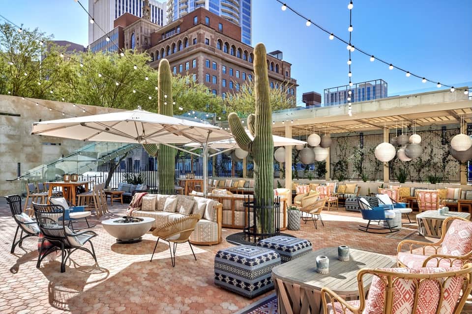 Upscale rooftop lounge with saguaro cactus, umbrellas, fire pit, and contemporary seating areas