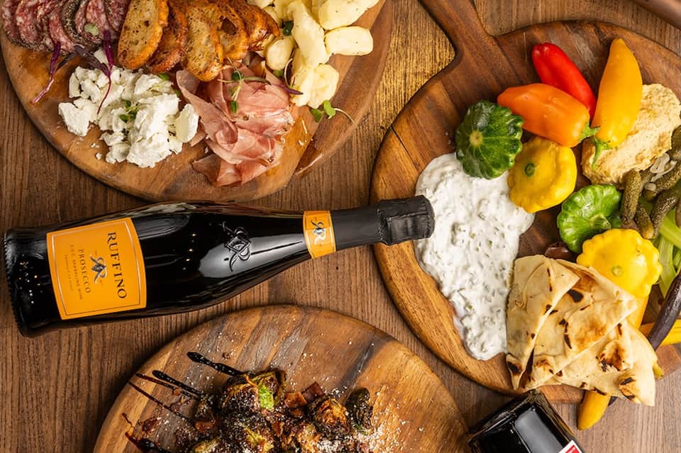 Gourmet charcuterie spread with cured meats, cheese, vegetables, bread, and champagne bottle