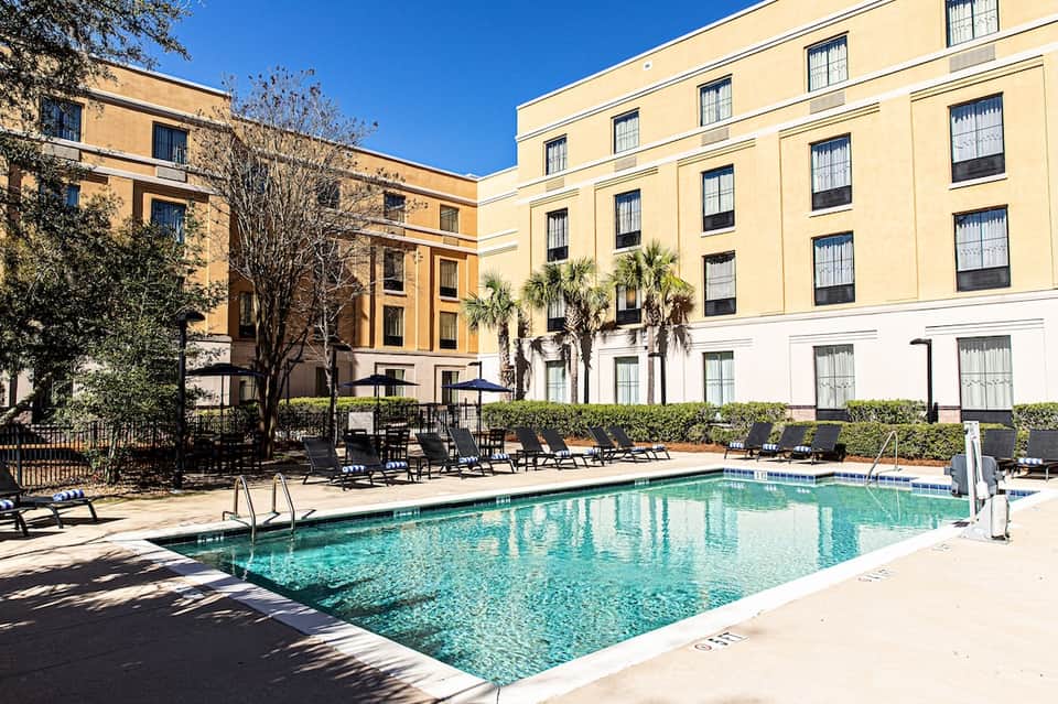 Resort courtyard pool surrounded by yellow and white historic building architecture with palm trees