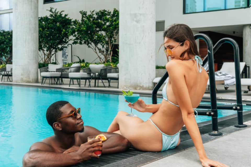 Guests enjoying poolside cocktails at modern resort with geometric architecture and water features