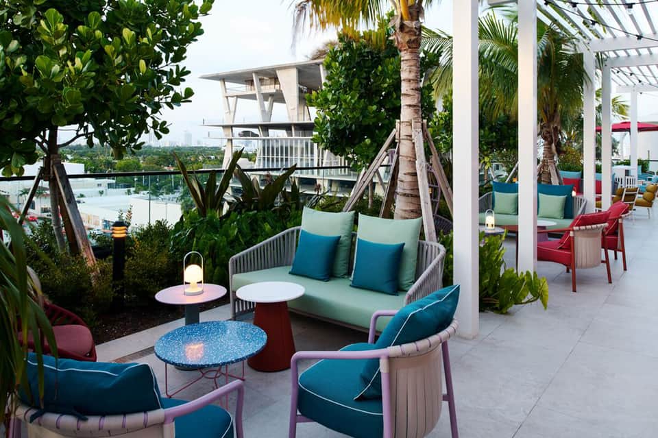 Waterfront patio lounge with tropical plants, colorful seating, and lake views