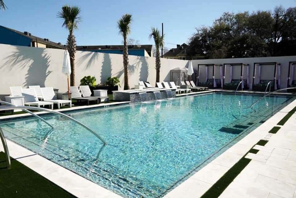 Resort pool with palm trees, white lounge chairs, and modern architecture