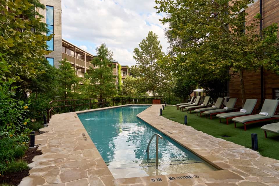 Resort swimming pool surrounded by lounge chairs and lush greenery