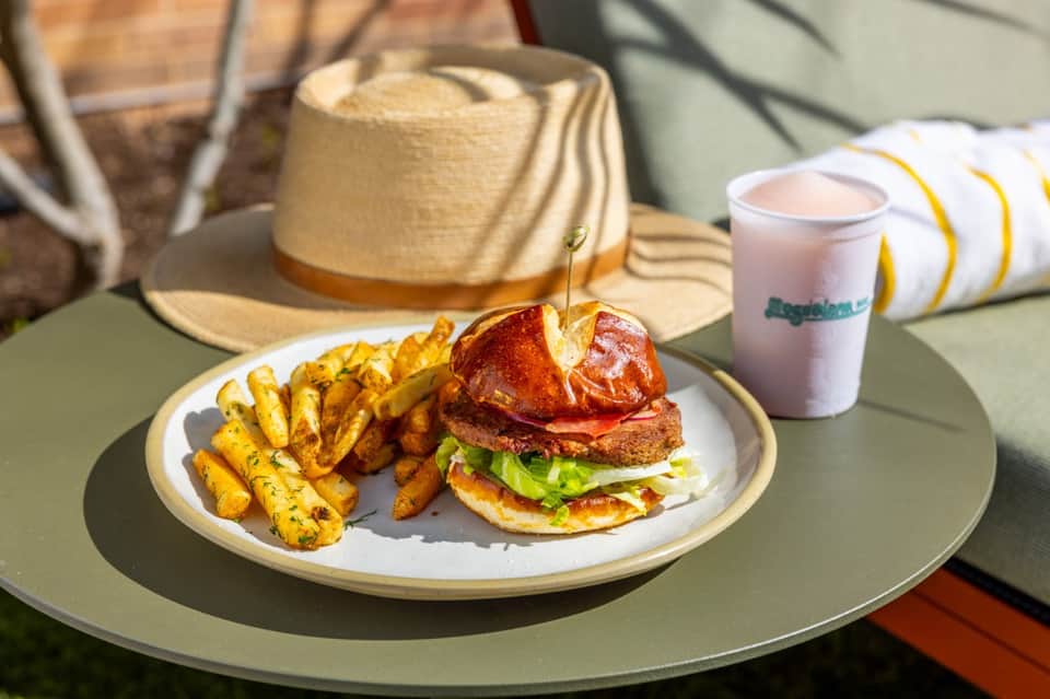 Outdoor dining with gourmet burger, fries, and beverage on sunny terrace