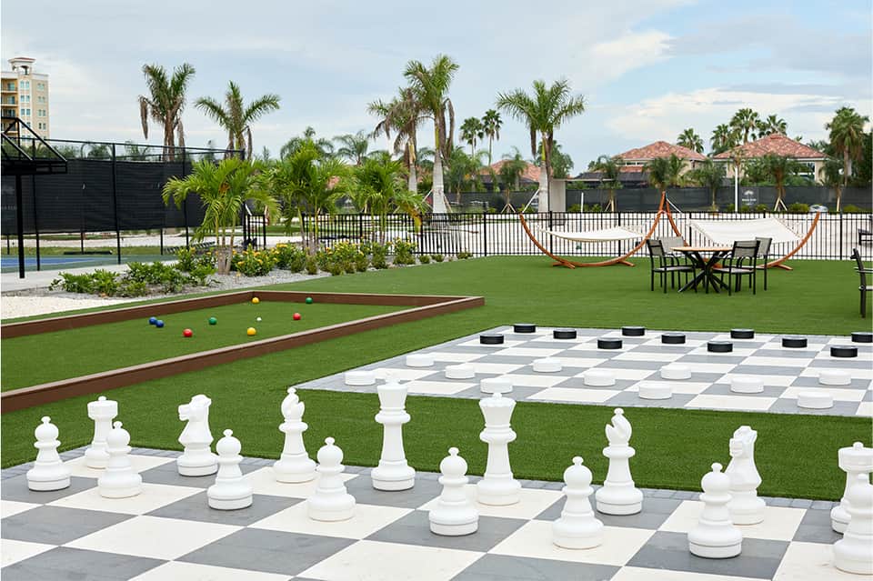 Resort lawn with giant chess set, bocce ball game, cornhole, giant checkers, and pool in background