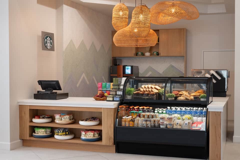 Starbucks café counter with woven pendant lights, pastry display case, and mountain-themed wall art