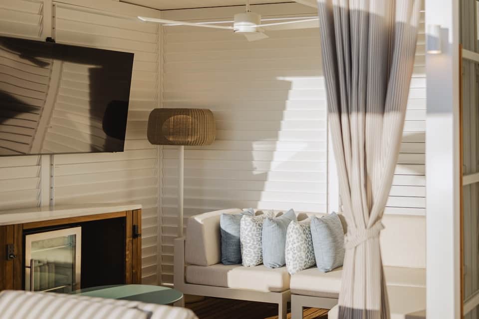 Luxury resort suite featuring white shiplap walls, entertainment unit with TV, and cozy window seating nook