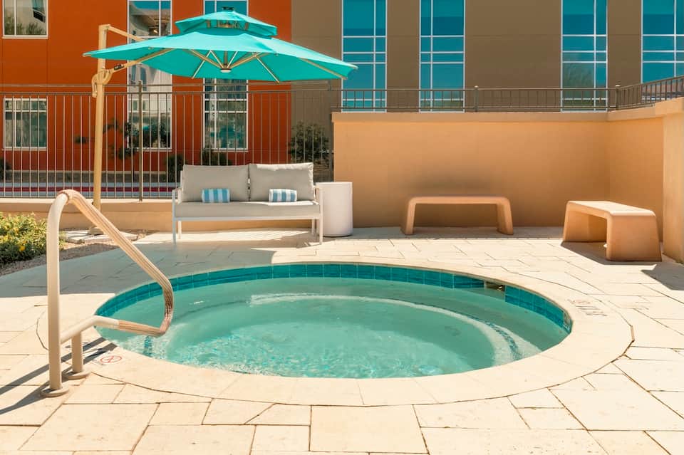 Outdoor hot tub on terrace with turquoise umbrella and ocean views