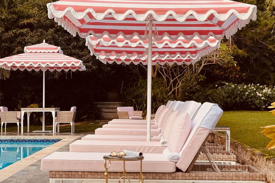 Red and white striped umbrellas and lounge chairs beside residential pool at dusk