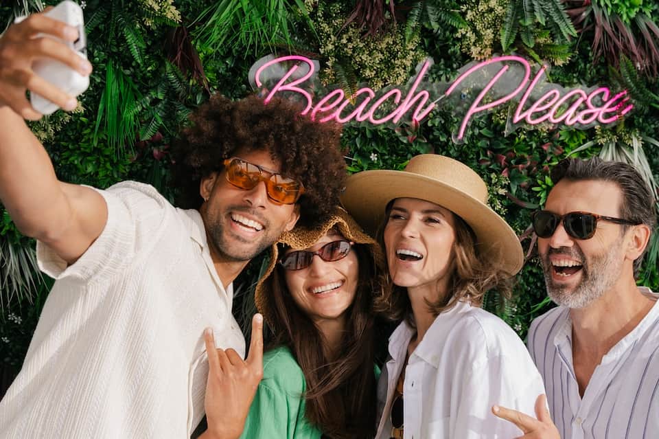 Group of four people posing at Beach Palace photo backdrop with tropical greenery