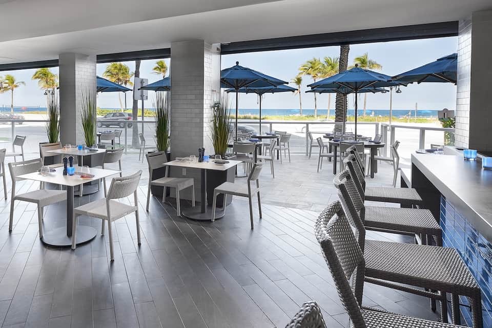 Beachfront dining terrace with tables, umbrellas, and ocean view