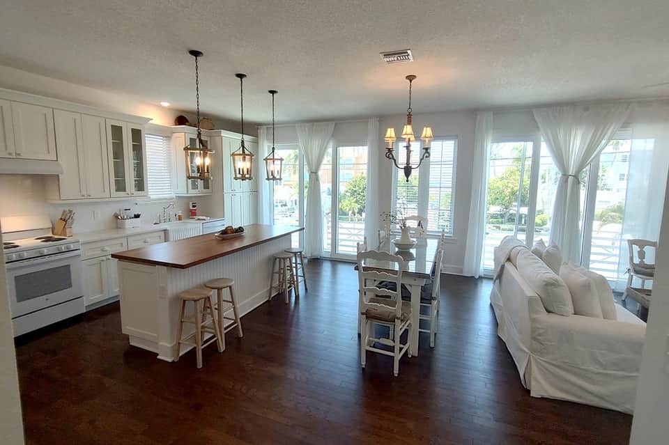 Open-concept hotel suite with modern kitchen, dining area, multiple pendant lights, and sliding glass doors