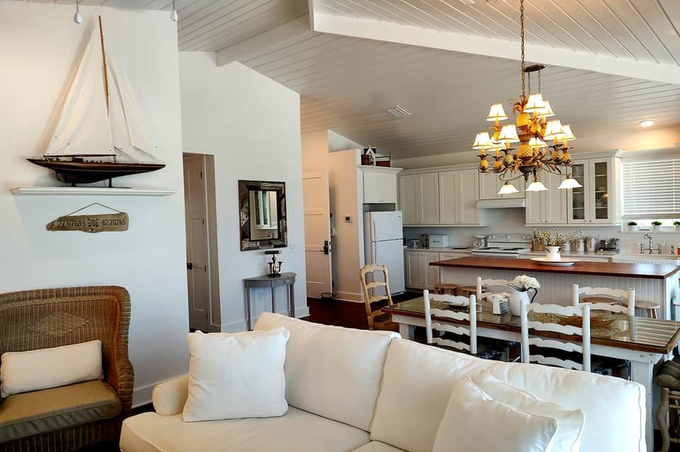 Coastal cottage living room with sailboat decor, fireplace, and open kitchen area
