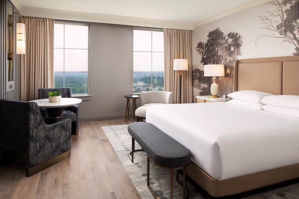 Upscale hotel bedroom with king bed, panoramic windows overlooking landscape, and contemporary furnishings