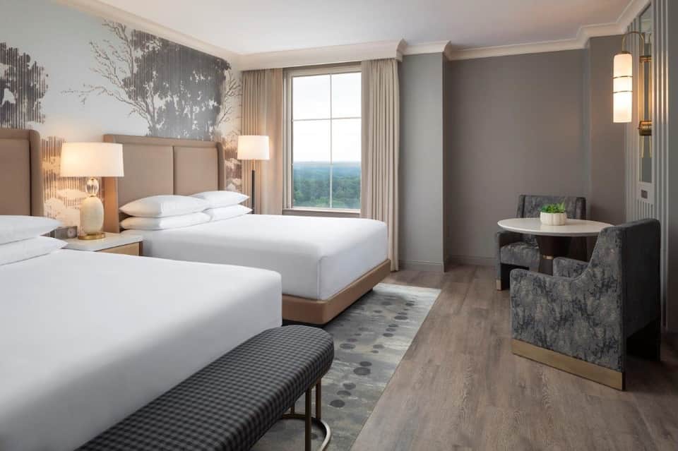 Spacious bedroom with two queen beds, beige headboards, and panoramic windows