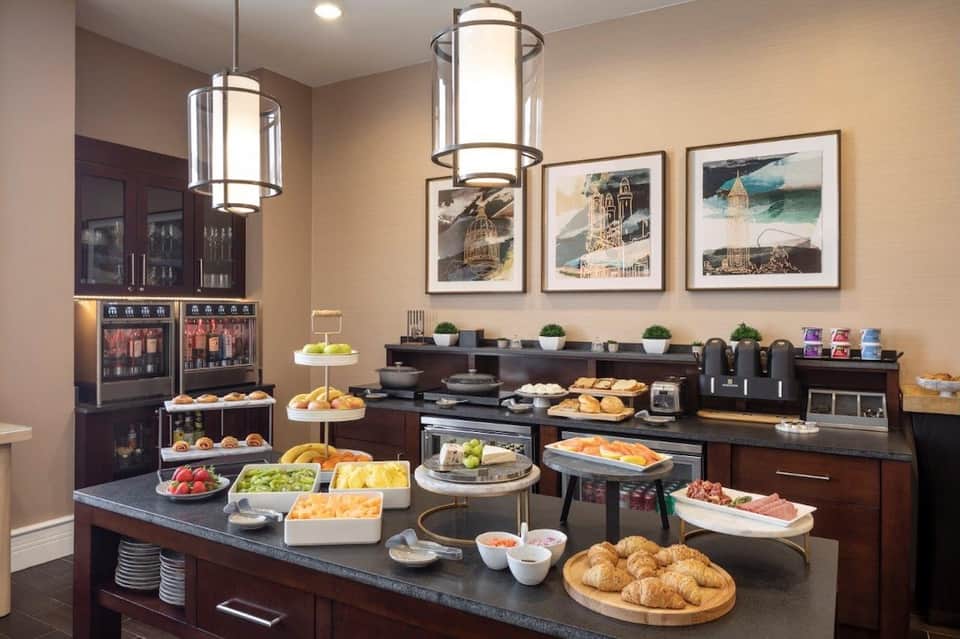 Breakfast buffet display with pastries, fresh fruit, cold cuts, and beverages