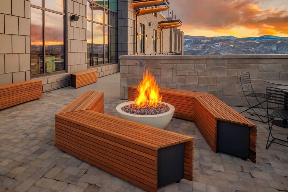 Rooftop fire pit area with wooden seating and mountain sunset views from hotel terrace