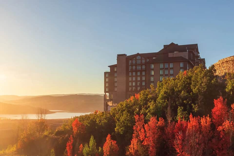 Red brick hotel building at sunset with autumn foliage and lake backdrop