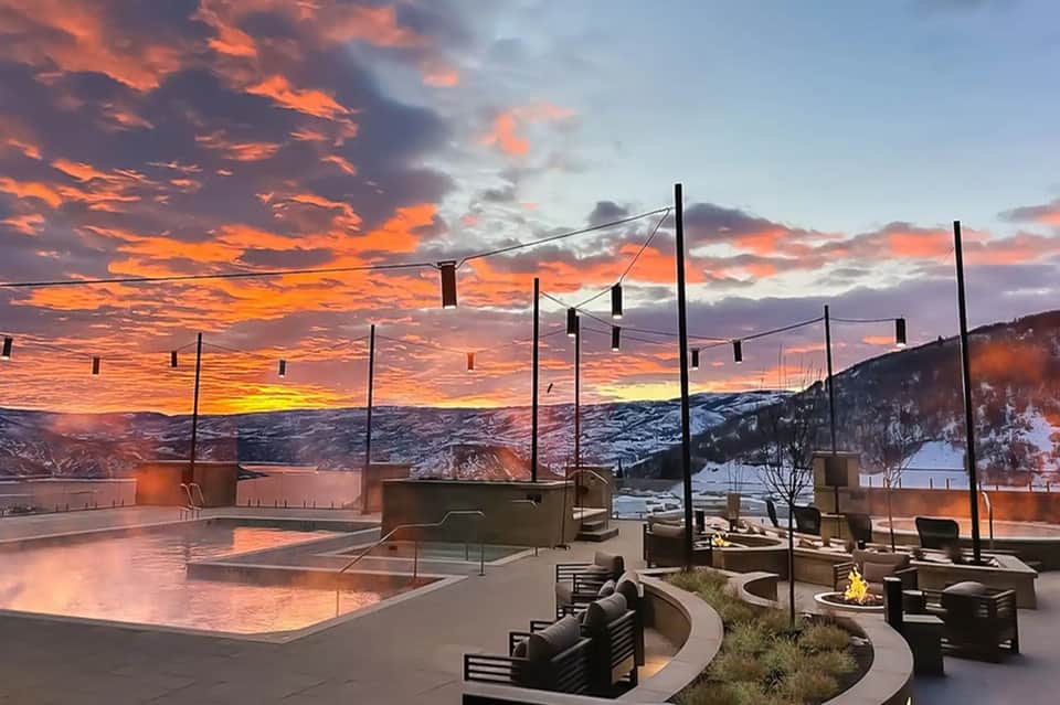 Modern resort deck at sunset with fire pits, lounge chairs, and panoramic mountain valley views