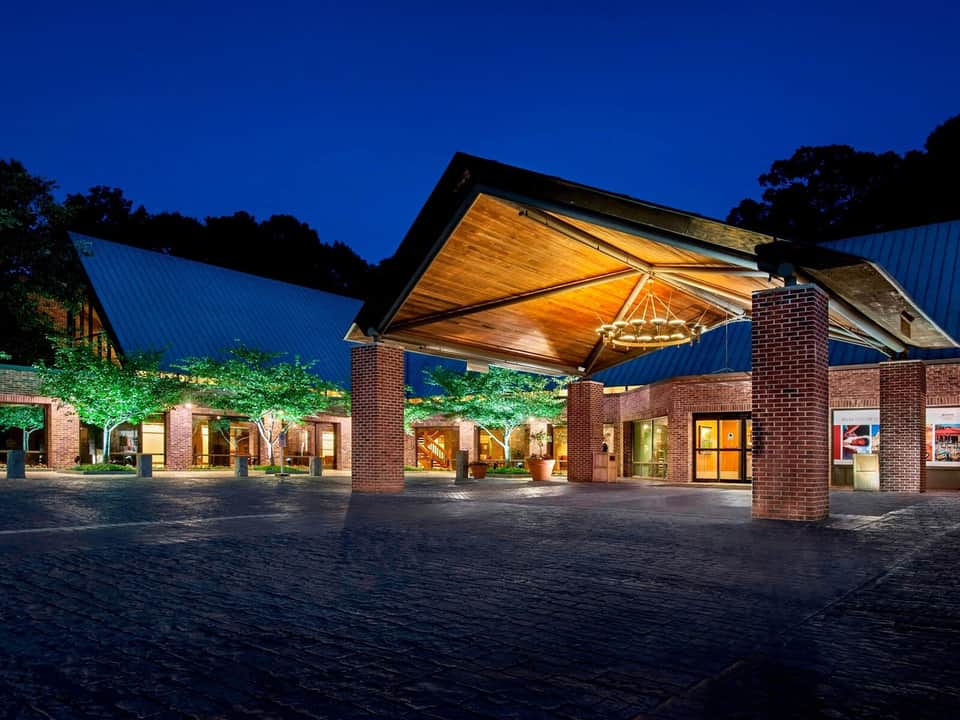 Modern brick pavilion entrance with wooden canopy illuminated at dusk