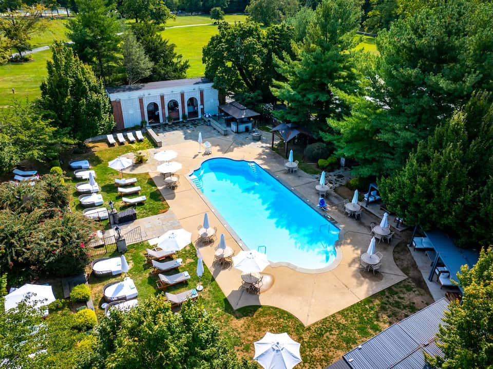 Aerial view of resort pool surrounded by loungers, umbrellas, and lush greenery